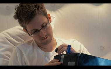 Snowden steckt eine SD-Karte in einen Laptop mit einem blauen Tails-USB-Stick